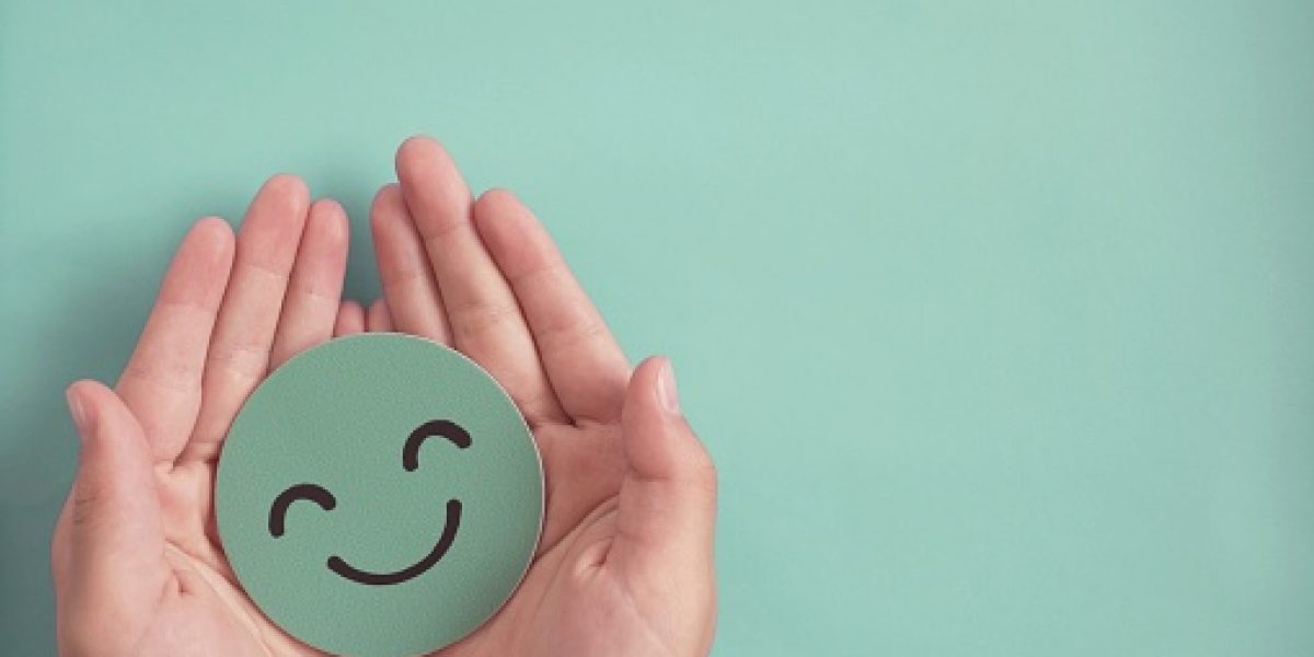 Hands holding green happy smile face paper cut, good feedback rating and positive customer review, experience, satisfaction survey ,mental health assessment, child wellness,world mental health day concept